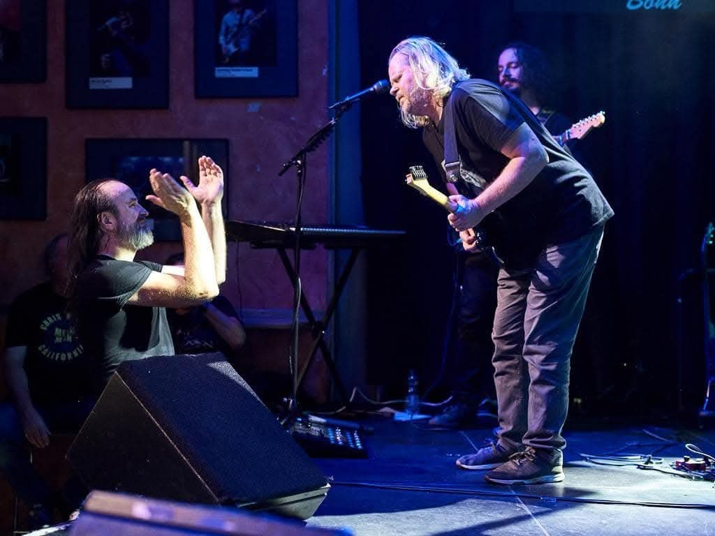 Damian Wilson applauding from the floor while Joop Wolters plays a solo on stage