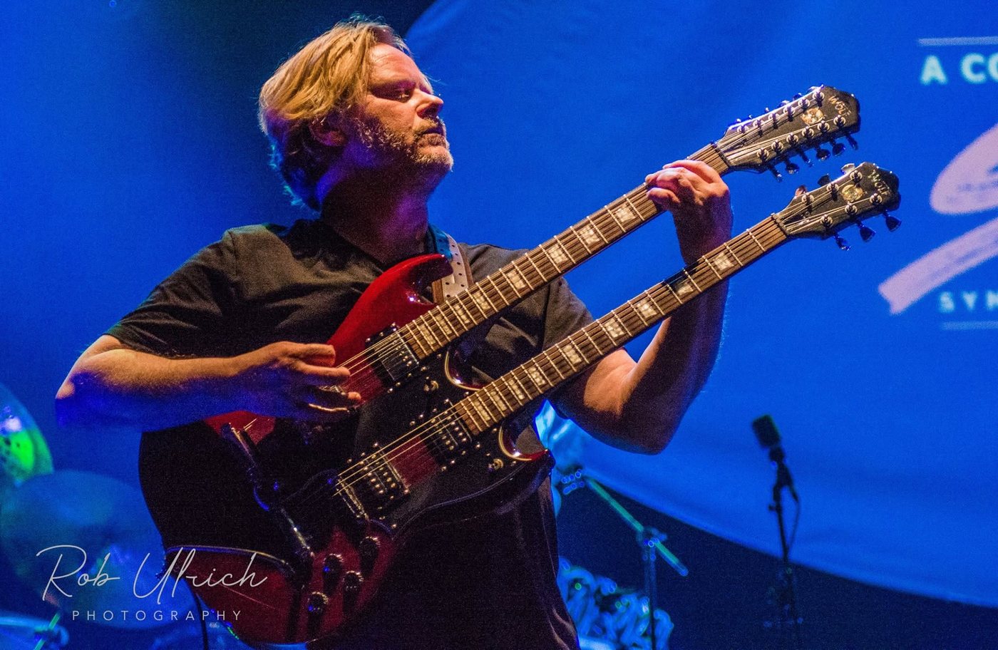 Joop Wolters playing a double-neck guitar on stage with Symphonic Rock Night